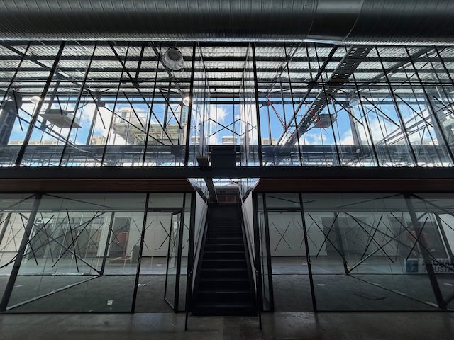 Modern industrial interior with a central staircase, glass walls, black metal frames expertly fabricated by Harris Steel Fab