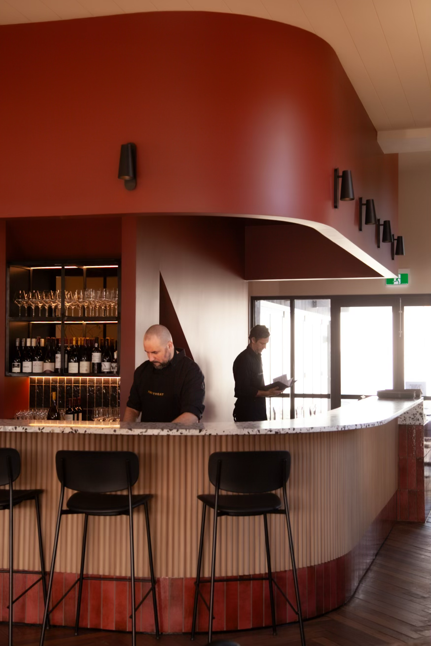 Geelong's newest French-inspired restaurant and bar - The Retreat. Two men working behind the bar. Red bar with terrazzo bench top and wooden panelling. 