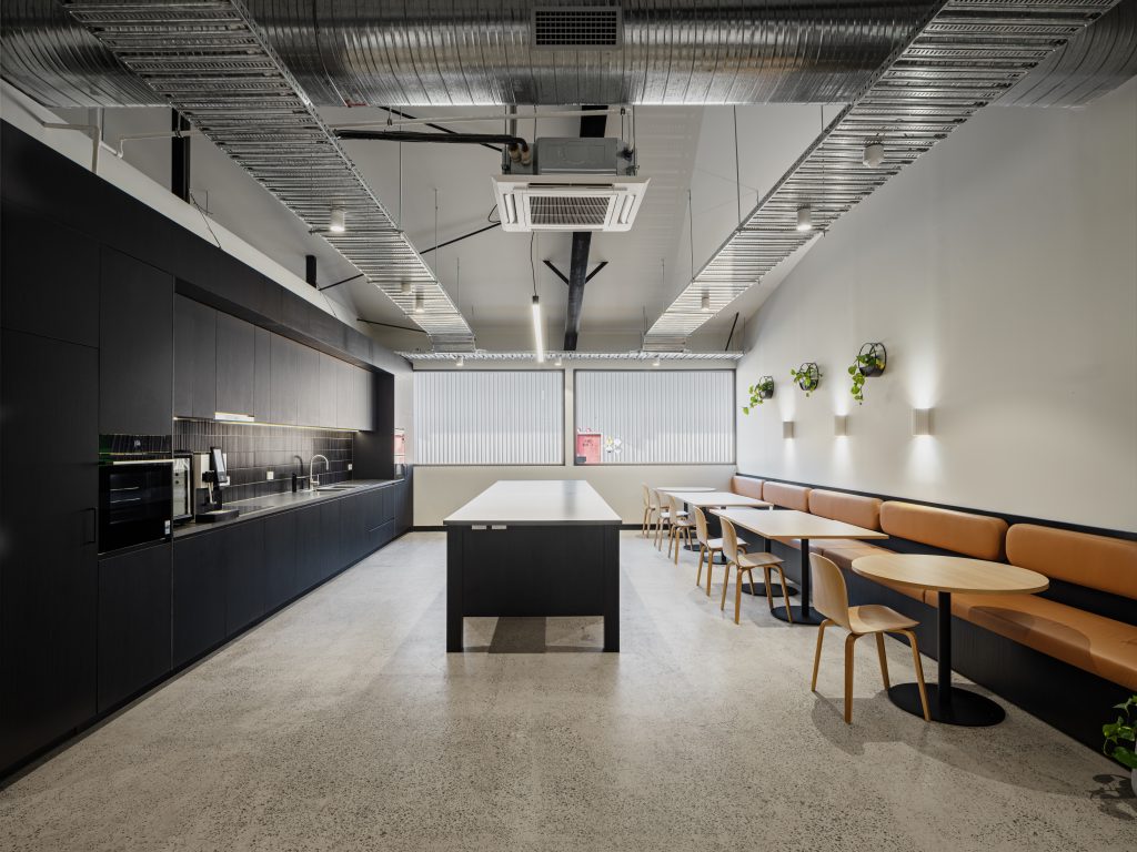 Office fit-out in Laverton North by Hamilton Group. Contemporary kitchen and breakout room featuring custom black cabinetry and built-in bench seating. The space is modern and spacious, designed for both functionality and comfort.